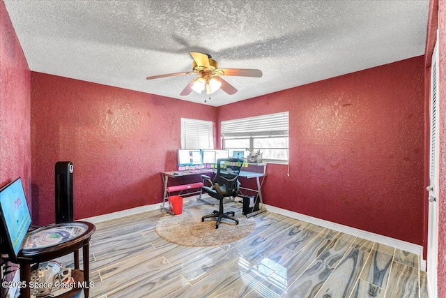 home office featuring ceiling fan, a textured wall, wood finished floors, and baseboards