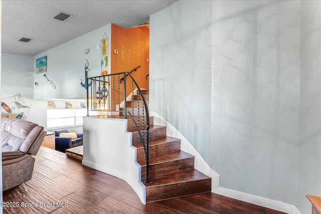 stairway featuring visible vents, baseboards, and wood finished floors