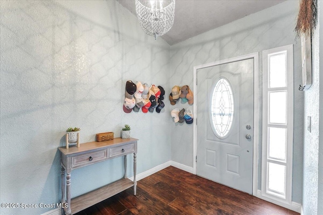 entryway featuring dark wood-style flooring, a notable chandelier, and baseboards