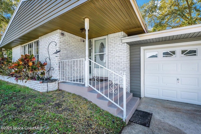 entrance to property featuring a garage and brick siding