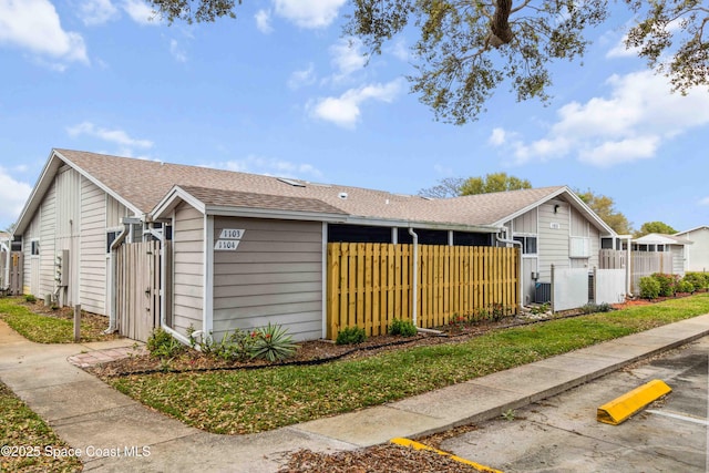 view of home's exterior featuring a shingled roof and fence