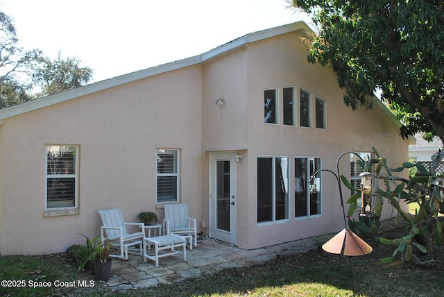 back of property with stucco siding and a patio