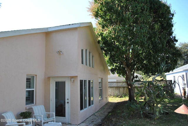 back of house featuring fence and stucco siding