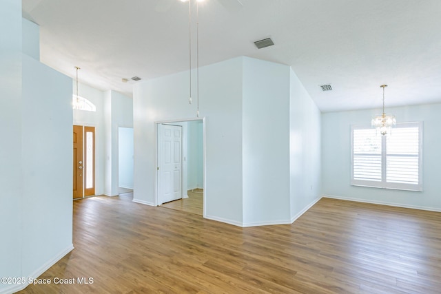 spare room featuring ceiling fan with notable chandelier, wood finished floors, visible vents, and baseboards