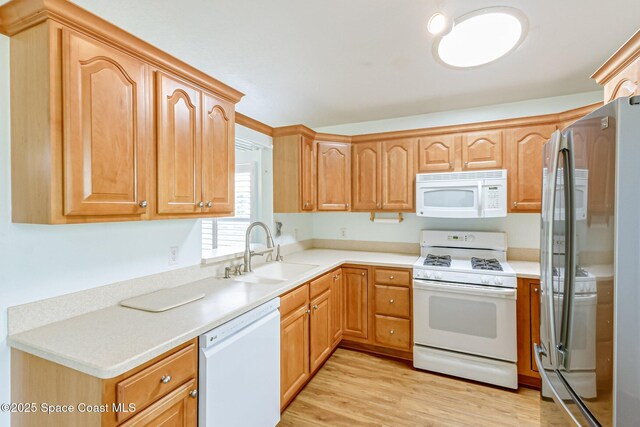 kitchen featuring white appliances, light wood-style floors, a sink, and light countertops