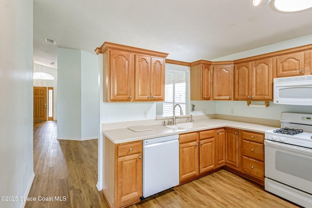 kitchen with white appliances, light wood-style flooring, a sink, and visible vents