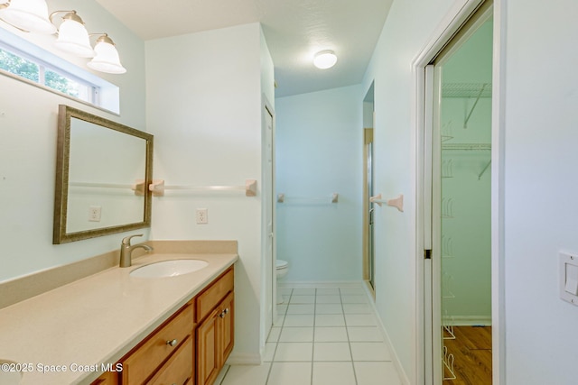 bathroom with toilet, tile patterned flooring, baseboards, and vanity