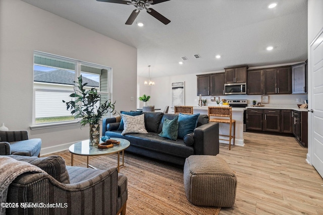 living room with ceiling fan with notable chandelier, light hardwood / wood-style flooring, and sink