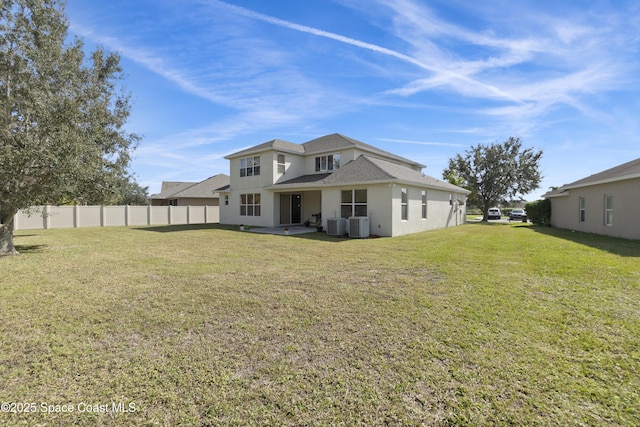 back of property with a yard, cooling unit, and fence