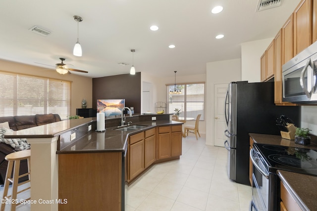 kitchen featuring a kitchen island with sink, a sink, visible vents, open floor plan, and decorative light fixtures