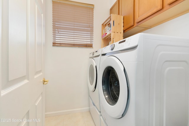 washroom with light tile patterned floors, washing machine and dryer, baseboards, and cabinet space