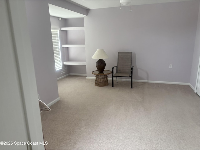 sitting room with baseboards and light colored carpet