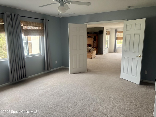 unfurnished room featuring light carpet, baseboards, a ceiling fan, and a healthy amount of sunlight