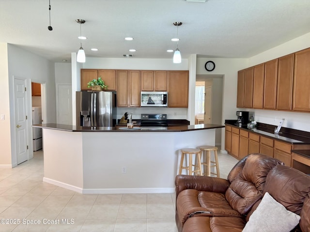 113 Wading Bird Cir SW, Palm Bay, FL 32908 - kitchen featuring stainless steel appliances, open floor plan, dark countertops, brown cabinetry, and washer / clothes dryer