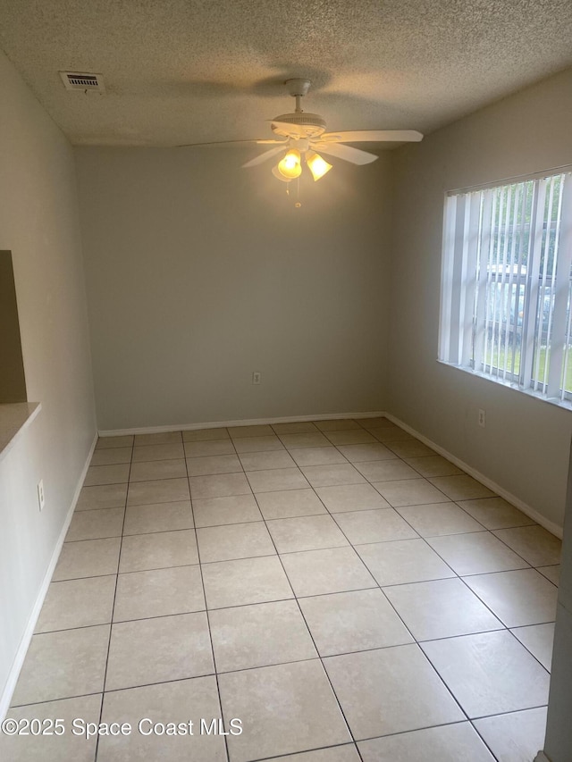 tiled empty room featuring a textured ceiling and ceiling fan