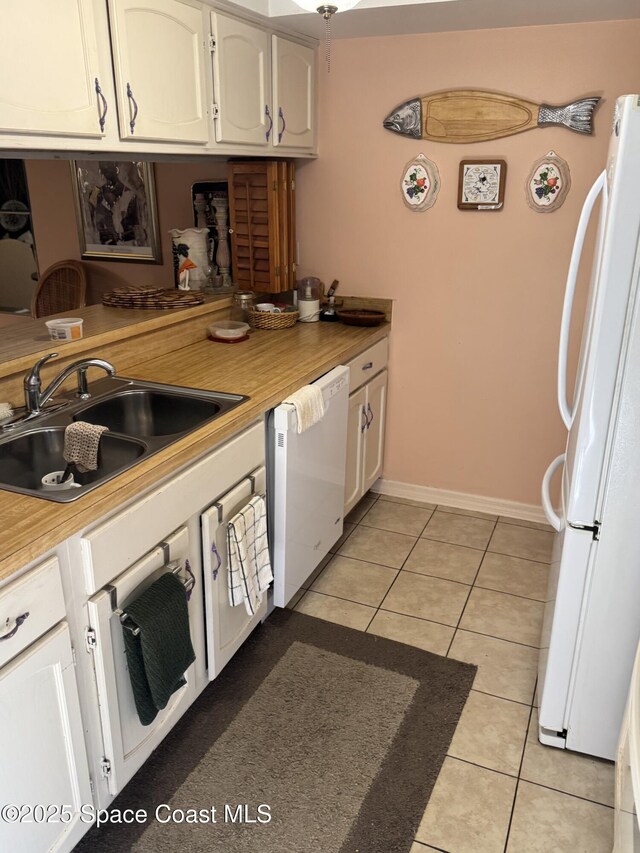 kitchen featuring white appliances, white cabinetry, sink, and light tile patterned floors