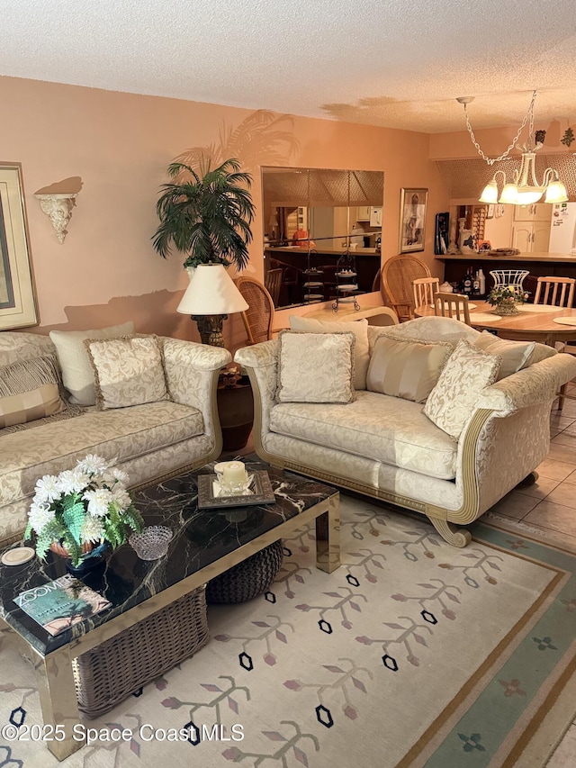 tiled living room featuring an inviting chandelier and a textured ceiling