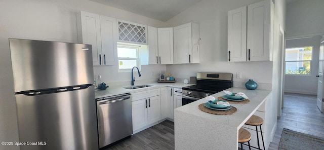 kitchen featuring appliances with stainless steel finishes, a breakfast bar area, dark wood-type flooring, sink, and white cabinetry