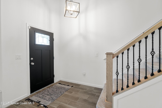 foyer featuring wood tiled floor, stairs, baseboards, and a chandelier