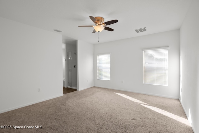 carpeted spare room featuring ceiling fan, visible vents, and baseboards