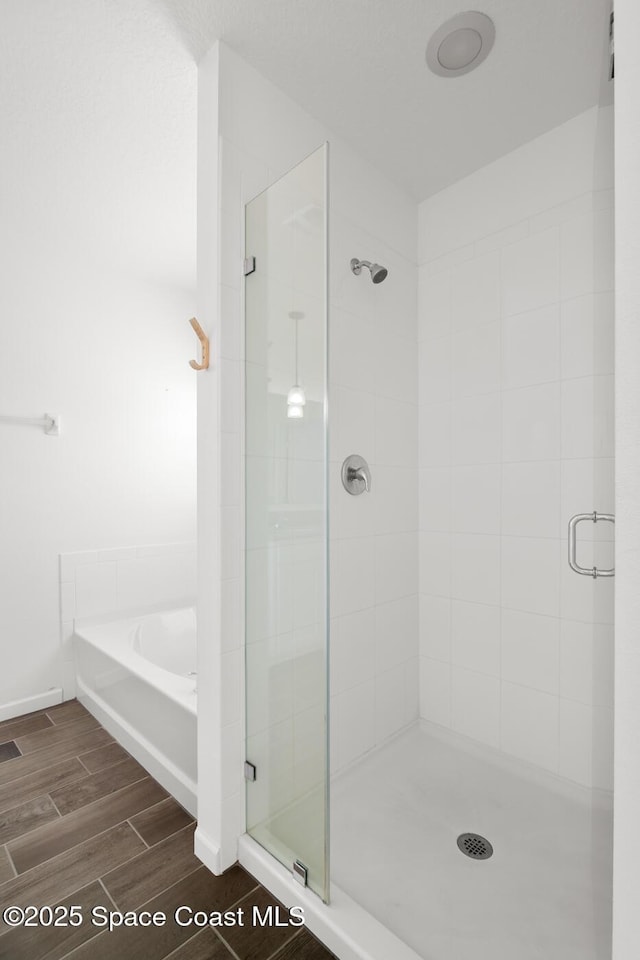 full bath with a stall shower, wood tiled floor, and a garden tub