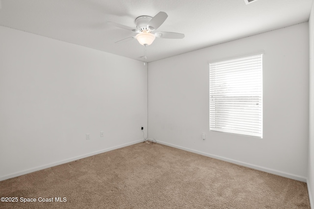 carpeted spare room featuring ceiling fan and baseboards