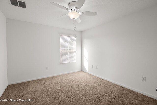 carpeted empty room featuring ceiling fan, visible vents, and baseboards