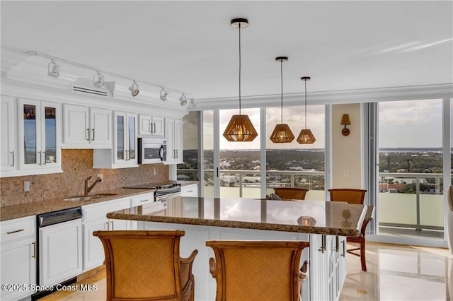 kitchen featuring a center island, white cabinets, decorative backsplash, stainless steel appliances, and a sink