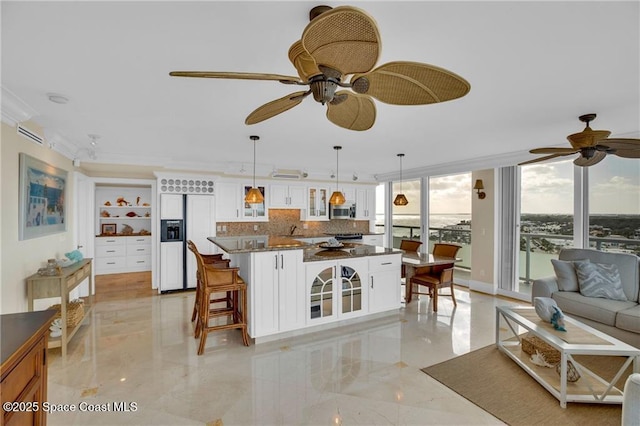kitchen with stainless steel microwave, paneled fridge, glass insert cabinets, and ceiling fan