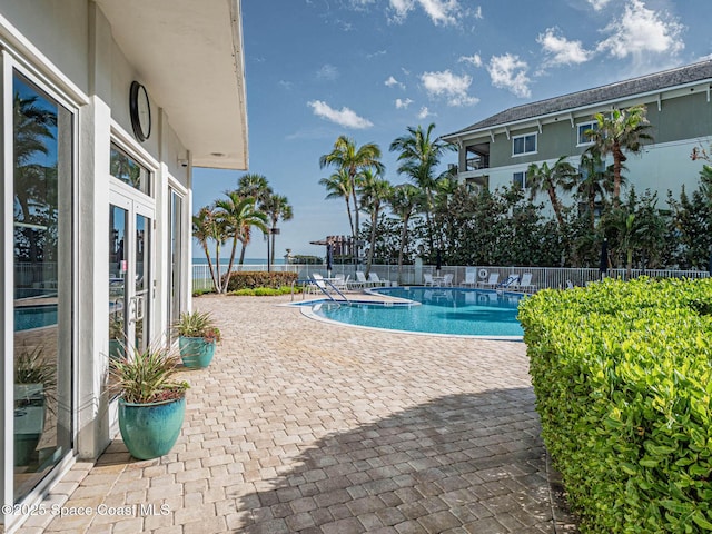 community pool with french doors, fence, and a patio