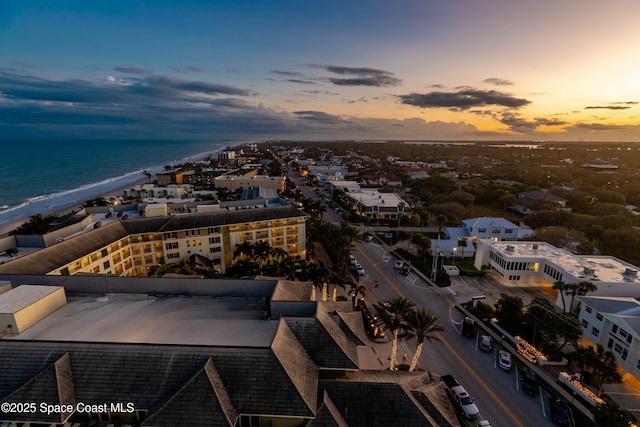 aerial view at dusk with a water view and a beach view