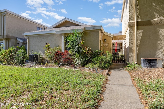 1040 Abada Ct NE Unit 109, Palm Bay, FL 32905 - view of side of home featuring stucco siding, a gate, a lawn, and central AC unit