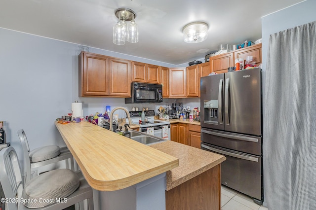 kitchen with kitchen peninsula, electric range oven, stainless steel fridge with ice dispenser, light tile patterned flooring, and a kitchen breakfast bar