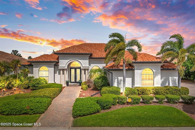 mediterranean / spanish home featuring a tiled roof, french doors, and stucco siding