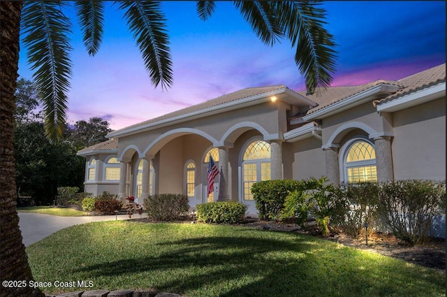 mediterranean / spanish home featuring a lawn