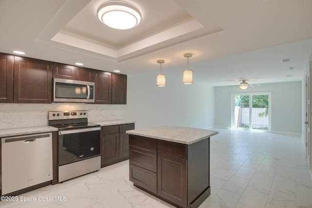 kitchen with appliances with stainless steel finishes, decorative light fixtures, a raised ceiling, and backsplash