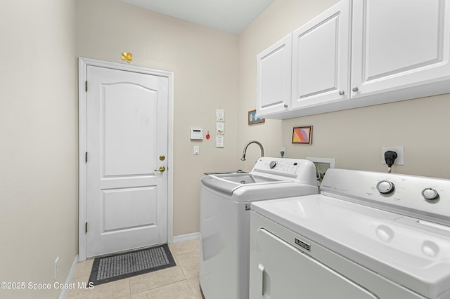 laundry room featuring light tile patterned floors, washing machine and clothes dryer, cabinet space, and baseboards