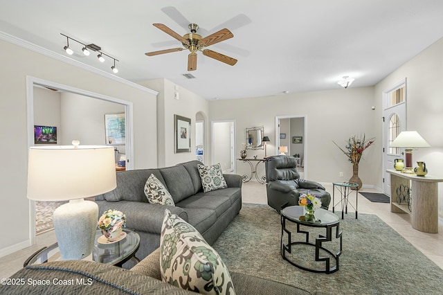 living area with arched walkways, ceiling fan, light tile patterned floors, visible vents, and baseboards