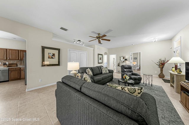 living room with arched walkways, light tile patterned floors, visible vents, a ceiling fan, and baseboards