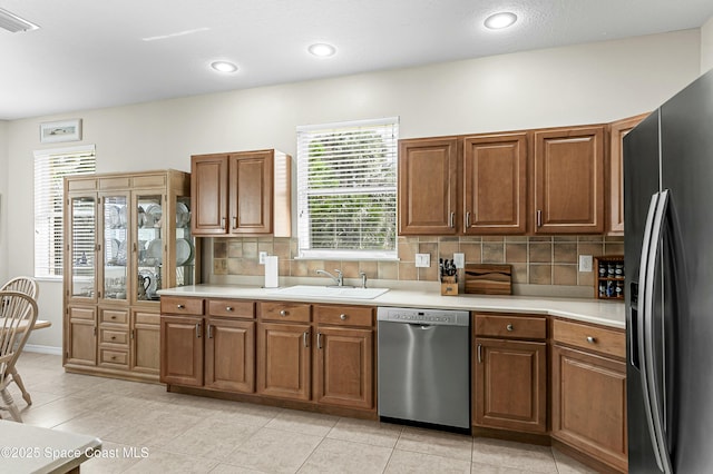 kitchen featuring light countertops, appliances with stainless steel finishes, brown cabinetry, and a sink