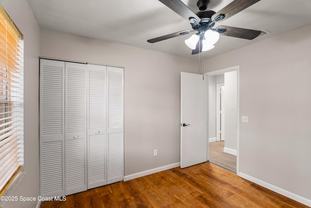 unfurnished bedroom featuring a ceiling fan, a closet, baseboards, and wood finished floors