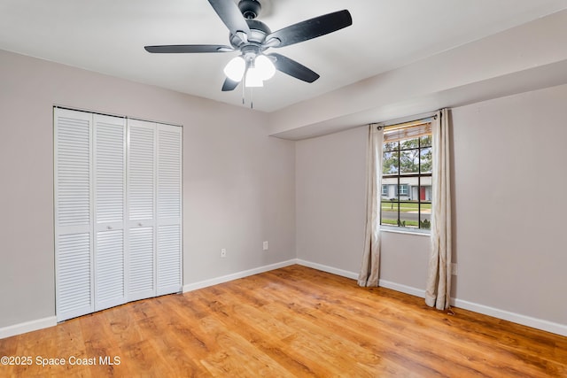 unfurnished bedroom with a ceiling fan, a closet, light wood-style flooring, and baseboards