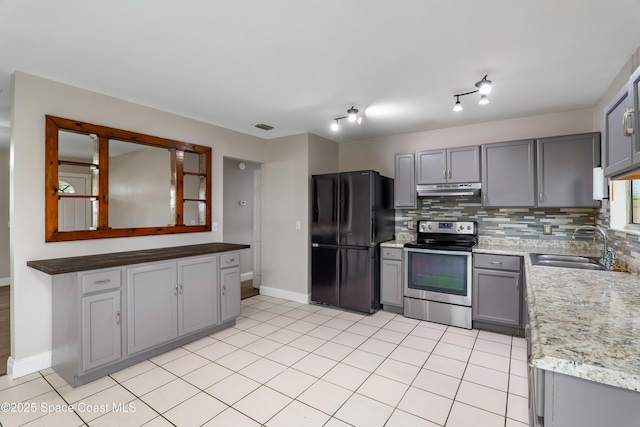 kitchen with stainless steel electric range oven, gray cabinets, freestanding refrigerator, a sink, and under cabinet range hood