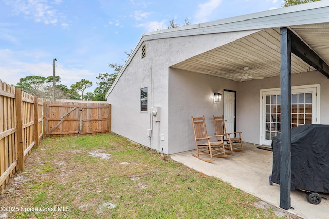 view of yard with a patio area, a fenced backyard, a gate, and ceiling fan