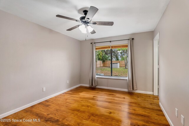 empty room featuring a ceiling fan, baseboards, and wood finished floors