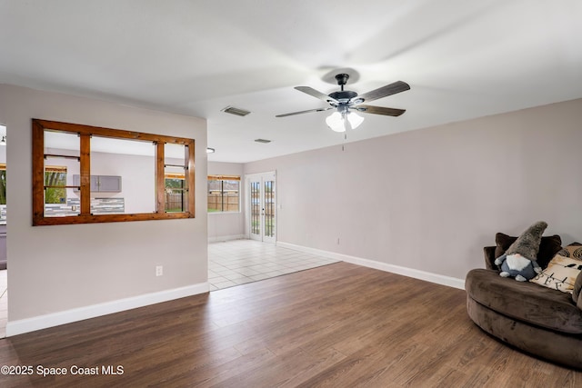 unfurnished living room featuring baseboards, visible vents, ceiling fan, and wood finished floors