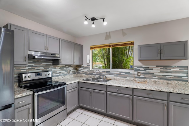 kitchen with appliances with stainless steel finishes, light stone countertops, gray cabinetry, under cabinet range hood, and a sink