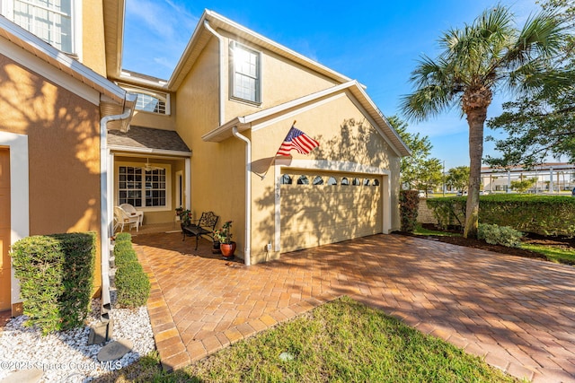 view of front of home featuring a garage, decorative driveway, and stucco siding