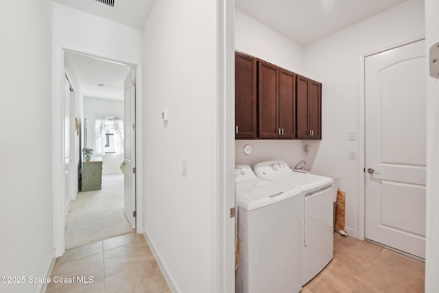 clothes washing area featuring light tile patterned floors, baseboards, cabinet space, and washer and dryer