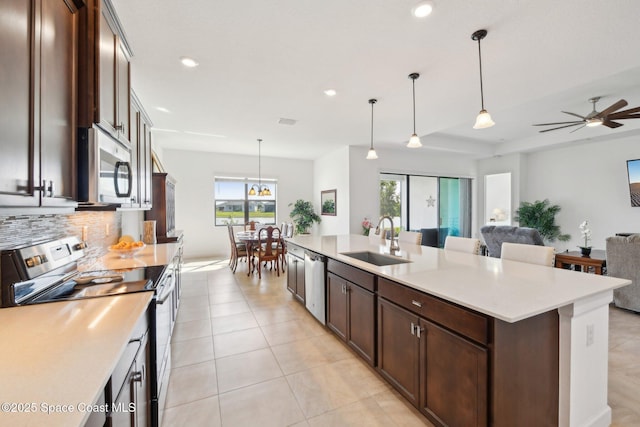 kitchen featuring light tile patterned flooring, a sink, light countertops, appliances with stainless steel finishes, and dark brown cabinets